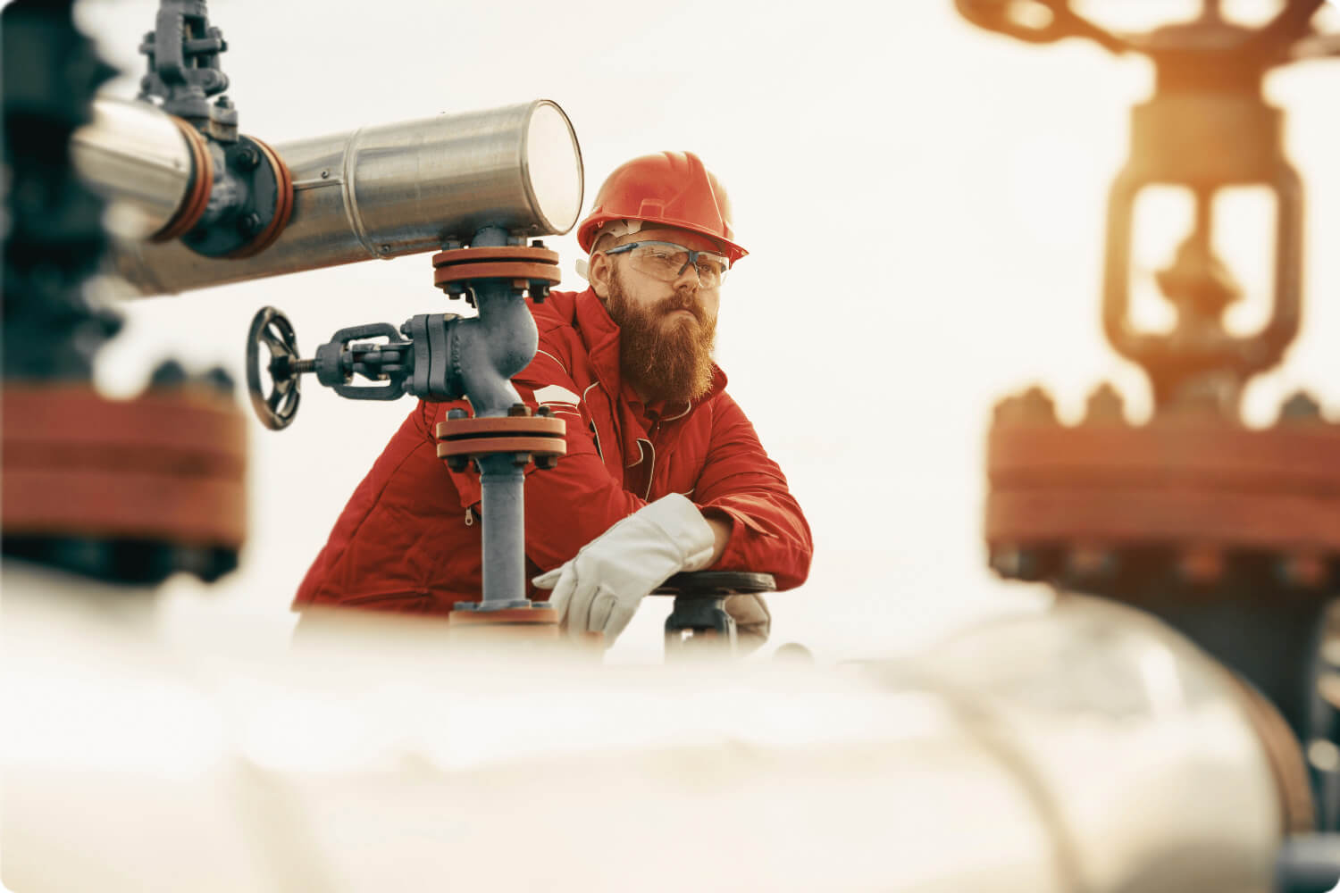 Worker in the field, leaning on pipe valve