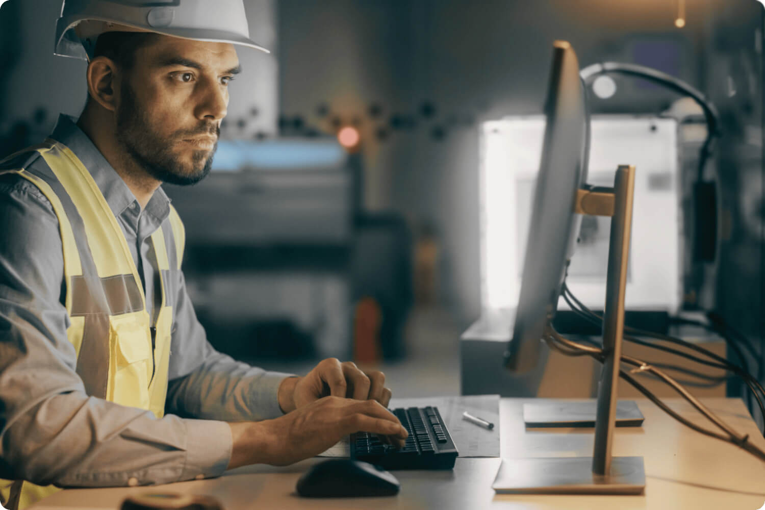 Worker in hard hat sitting at computer
